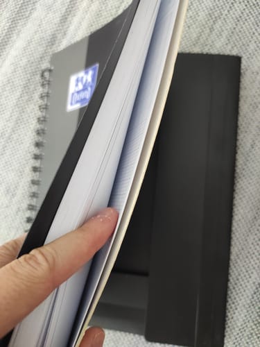 Customer's main montrant l'intérieur d'un cahier Oxford Nomadbook avec des pages lignées et une couverture noire.