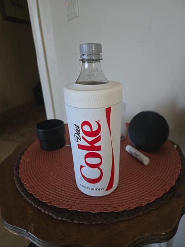 Customer's white Diet Coke Universal XL sleeve holding a soda bottle, standing on a round table.