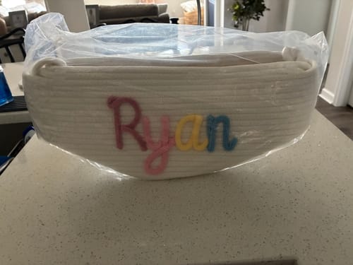 Customer's personalized white cotton Baby Knits basket inside clear plastic packaging, featuring the name Ryan in color.