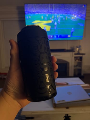 Customer's black Chicago Cubs Universal Buddy can cooler held in hand while watching a game on TV.