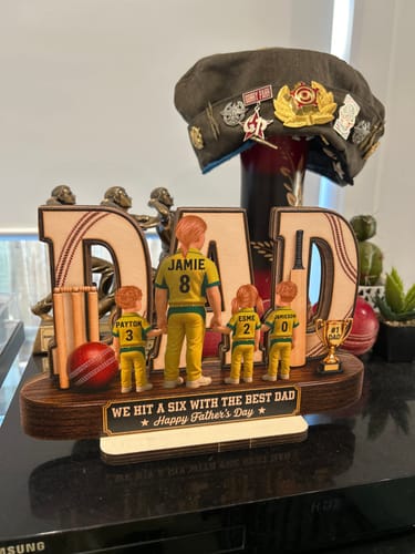 Customer's Cricket Dad personalized wooden plaque on a display surface, featuring jersey figures and cricket details.