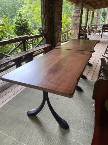 Customer's Curva dining table legs supporting wooden slab tables on a wooden porch.