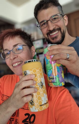 Customer's Bee Kind and Peeps Universal Buddy can coolers held by two people smiling at the camera.