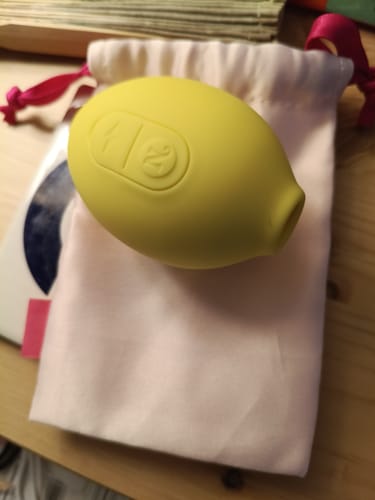 Customer's yellow Lem clitoral massager resting on a small, light-colored cloth pouch.