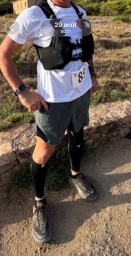 Client portant des compressions mollets Flytex V2 noires sur un sentier lors d'un trail.