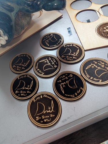 Reviewer's AtomStack P1 laser engraver projects showing multiple circular wooden tokens with engraved lettering.