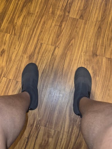 Customer's pair of black Otishi 2.0 Amaru Black gym shoes worn on feet on a wooden floor.