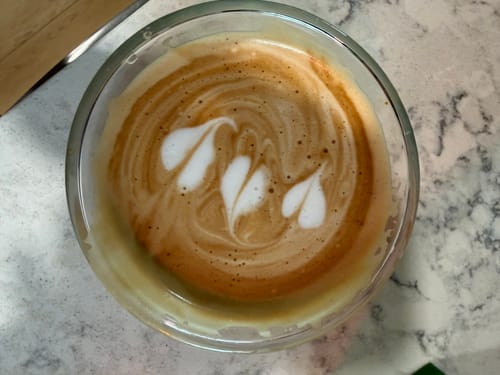 Customer's FLUR Latte XL Glass filled with a fresh latte showing detailed foam heart art