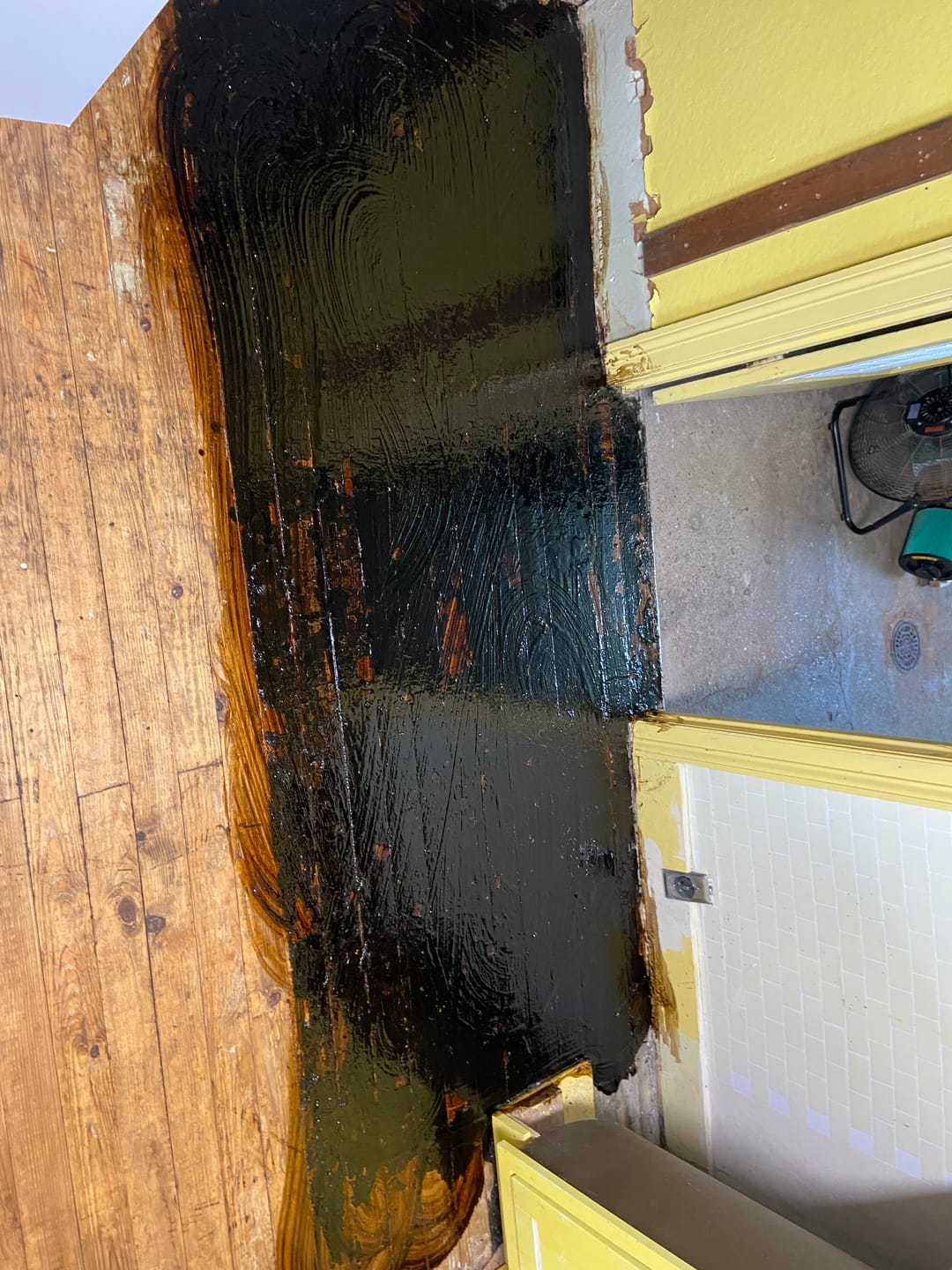 Thick black adhesive being stripped off an old wood kitchen floor with Floor Stripper