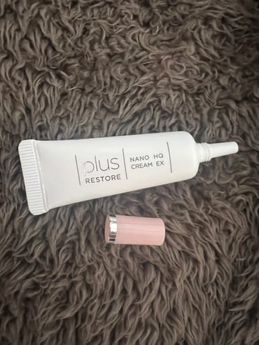 レビューアーのナノHQクリームEXの白いチューブと、その隣に置かれたピンク色のキャップのレビュー写真。