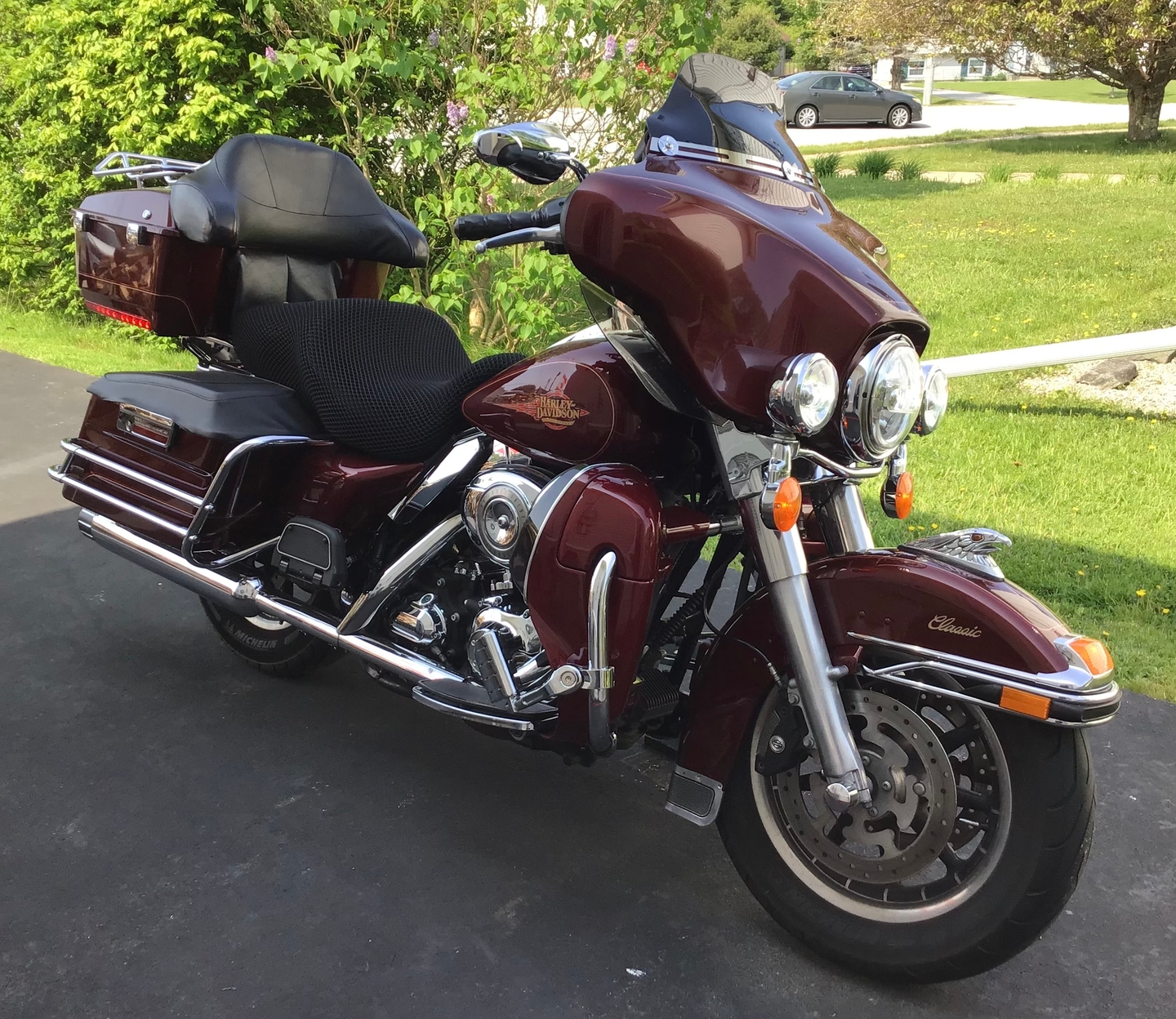 Burgundy Harley touring bagger parked outdoors with the Wind Rider 3D mesh seat cover installed on the seat