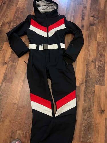 Customer's navy one-piece ski suit with color-block stripes laid flat on a wooden floor.
