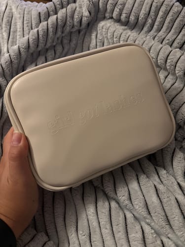 Eine Kundin hält die geschlossene, beigefarbene GirlGotLashes Mini Bag in der Hand.