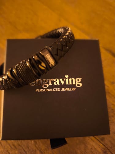 Close-up of a customer's black braided bracelet resting on its black gift box.