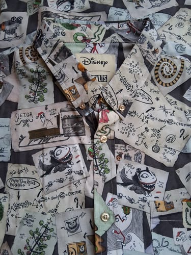 Close-up of a customer's 'Christmas Screamatics' shirt, showing the detailed print of Jack Skellington's brainstorm sketches.