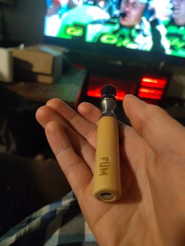 Customer holding a light-colored wooden FÜM device in the palm of their hand.