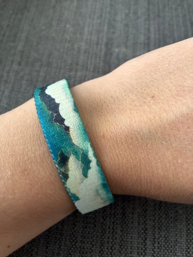 Close-up of a customer's wrist wearing the teal and white Break the Clouds Bracelet.
