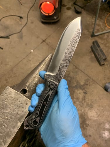 Reviewer holds a custom knife with a ground blade, a result of using the EdgeCore Ceramic Grinding Belts.