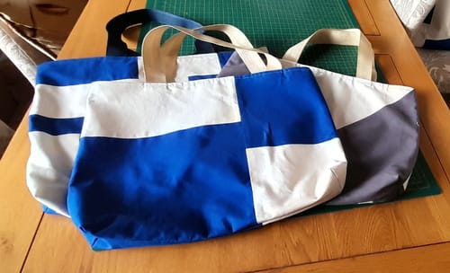 Customer's three finished tote bags made with the soft cotton canvas fabric in blue, white, and grey color blocks.