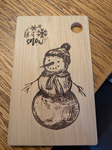 Reviewer's wooden cutting board with a festive snowman design, shown after being treated with the cutting board oil.