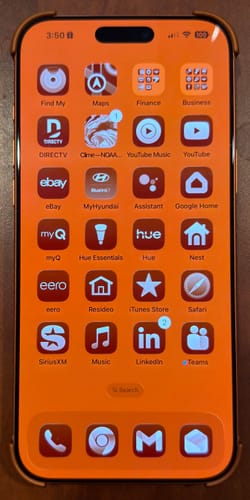 Reviewer's photo of the front of an iPhone in a case, displaying a bright orange home screen.