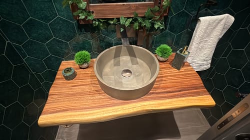 Reviewer's green marble circular incense dispenser on a wooden bathroom vanity next to a sink.