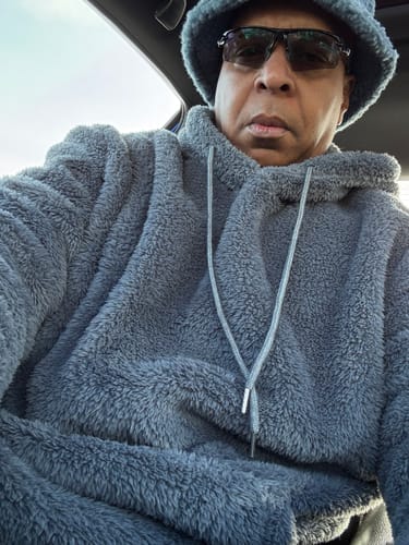 Reviewer wearing a fuzzy gray hat and matching hoodie while sitting in a car.