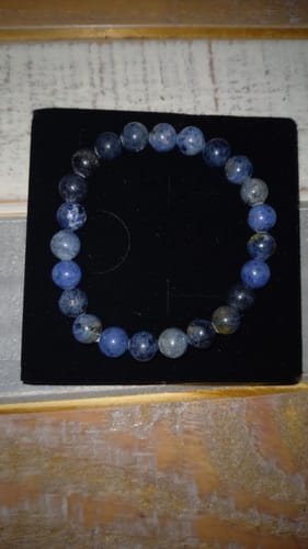 Le bracelet Dumortiérite d'un client, avec des perles bleues nuancées, posé sur un présentoir noir.