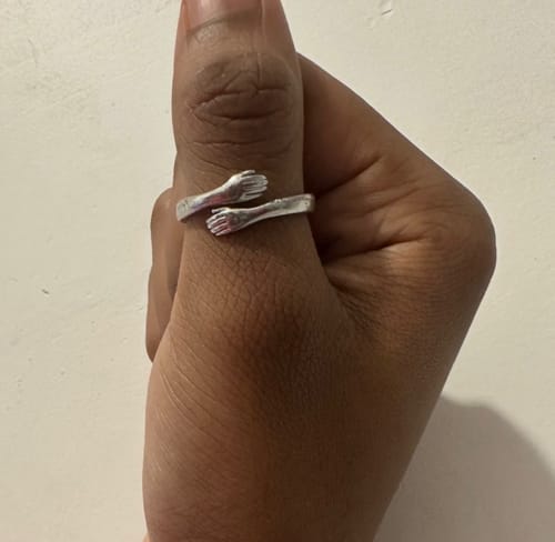 Customer wearing the silver Hug Ring, designed as two arms hugging a thumb.