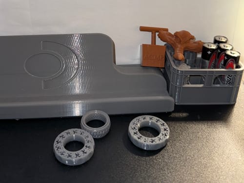 Reviewer's photo of various items 3D printed with the grey Budget PETG filament, including rings and a small crate.