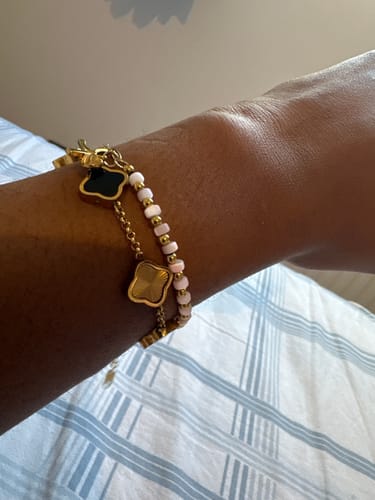 Customer's wrist wearing the Ribbon Beaded Bracelet, showing its double-strand design with pink beads and clover charms.