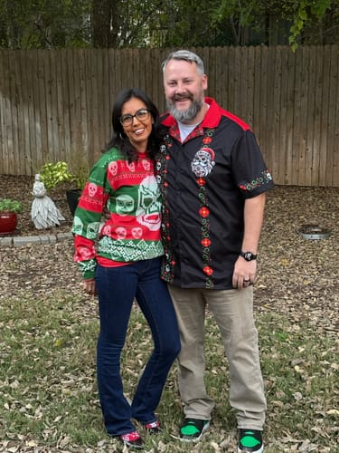 Customer wearing the black El Sancho Clause Guayabera holiday shirt while standing outdoors with a companion.