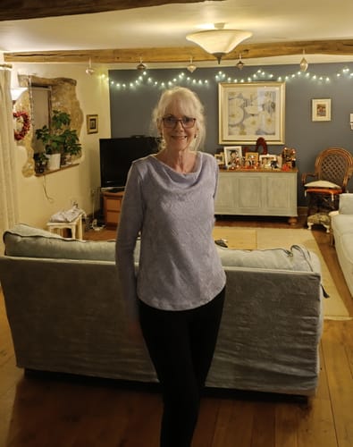 Reviewer standing in a living room wearing a mauvey-blue cowl neck top made from the Soft Melange Jacquard Knit Fabric.