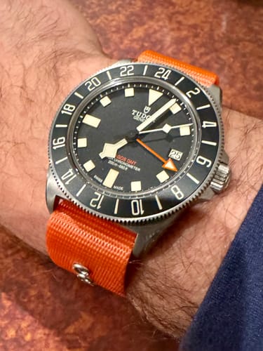 Customer's Tudor watch with the bright orange Alpha3 - Tango Tangerine strap on their wrist.