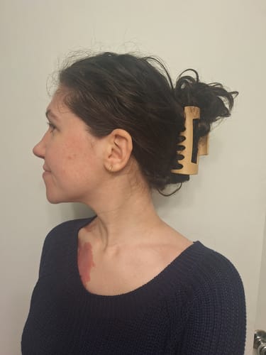 Reviewer's thick, dark hair held up in a messy bun with a light-colored Cloud Clip.