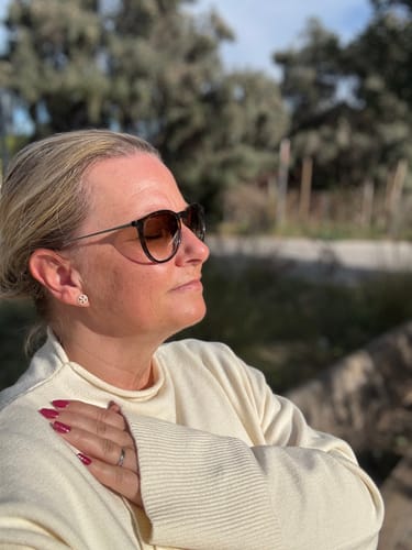 Reviewer outdoors wearing the Iris Knitted Lounge Oversized Sweater, with her hand on her chest feeling the soft fabric.