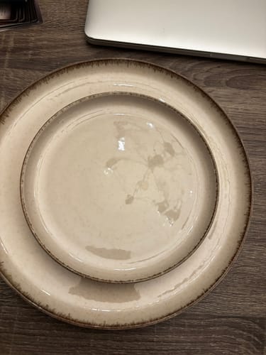 Klant toont een glanzend beige bord met een kleiner bord erop van de by fonQ Loods serviesset.