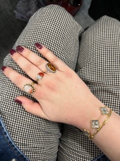 Customer's hand wearing the Toi Et Moi Birthstone Ring with two reddish stones, alongside other rings.