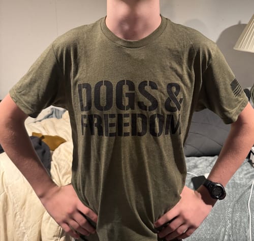 Customer's son wearing the olive green Dogs & Freedom Tee, showing the athletic fit and front graphic.