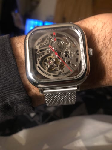Cliente mostrando su reloj Ciga Design C Series Skeleton en la muñeca, destacando su correa de malla de acero y su caja plateada.