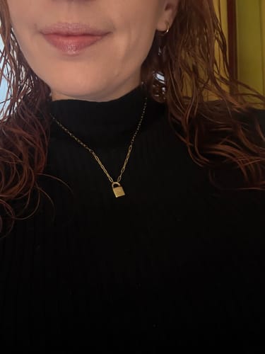 A reviewer wears the gold Engravable Padlock Necklace over a black high-neck top.