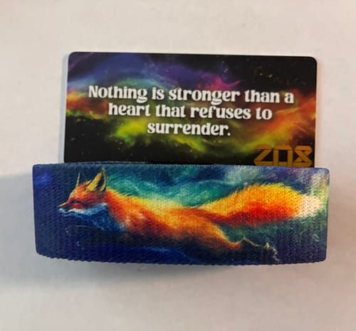 Customer's 'Against All Odds' bracelet showing a vibrant fox against a colorful space background with its message card.