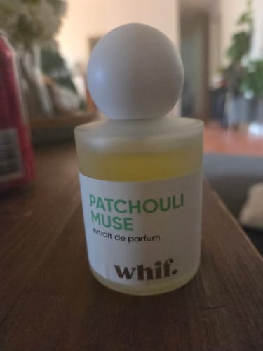 Customer's Patchouli Muse extrait de parfum in its frosted bottle with a round white cap, sitting on a wooden surface.