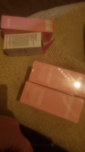 Klant toont de roze verpakking van het Bio-Collageen Masker, met één doosje open en twee nog in de verpakking.