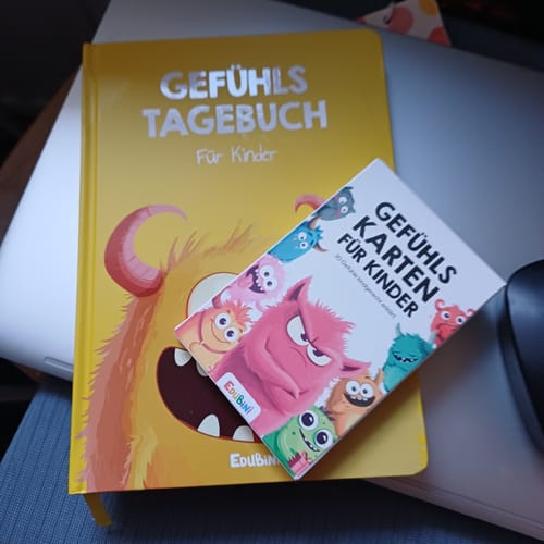 Rezensent zeigt die Edubini Gefühlskarten für Kinder zusammen mit dem passenden Gefühlstagebuch.