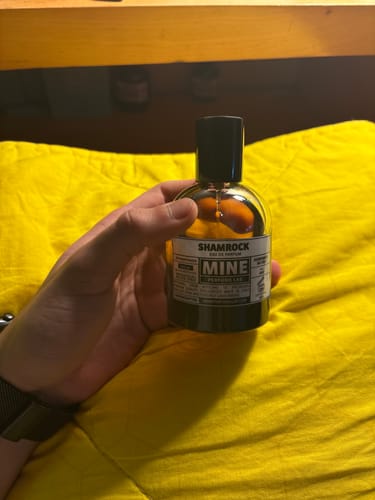 Recensore tiene in mano la boccetta di vetro ambrato del profumo SHAMROCK.