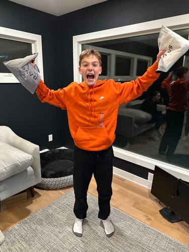 An excited customer holds up the packaging containing their Joshua 1:9 'Lion' Youth Performance Shorts.