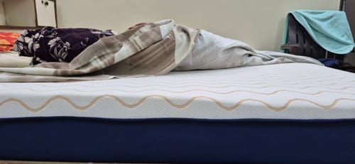 Customer's Flo Mattress Ortho on a bed, showing the white patterned top layer and blue base.