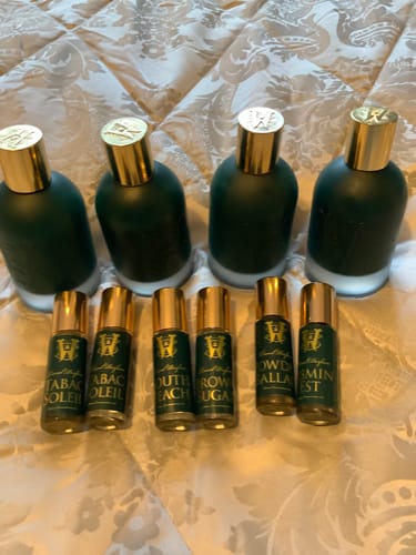 Customer's collection of perfumes in dark green bottles, including a rollerball of Brown Sugar.