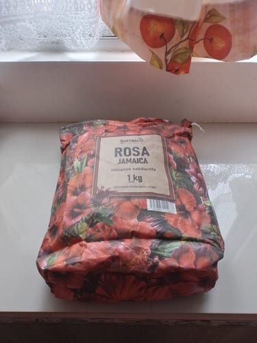 Un cliente muestra la bolsa de 1 kg de Rosa Jamaica bien embalada sobre una repisa.